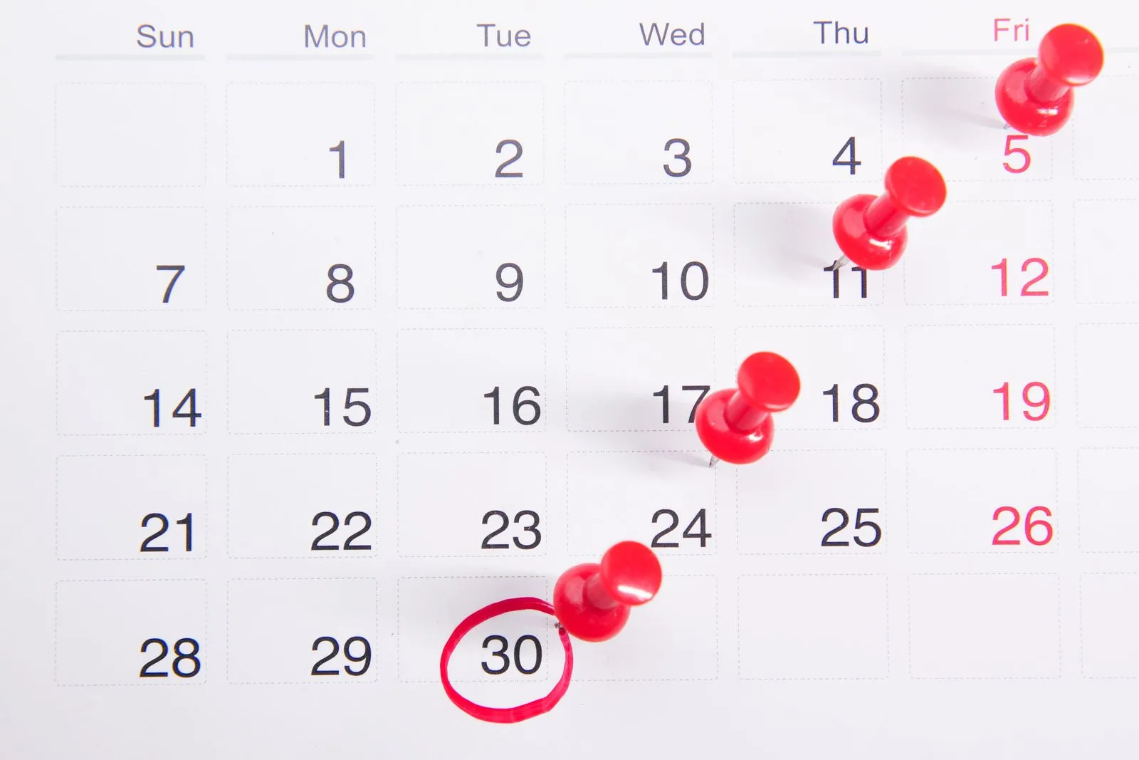 Red pins marking dates on a calendar