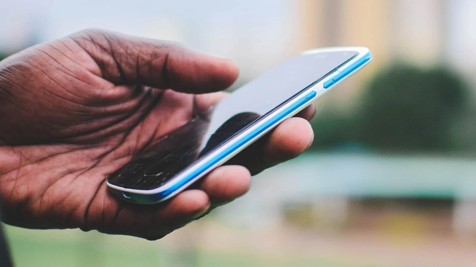 Close-up of a hand holding a smartphone outdoors in Nairobi